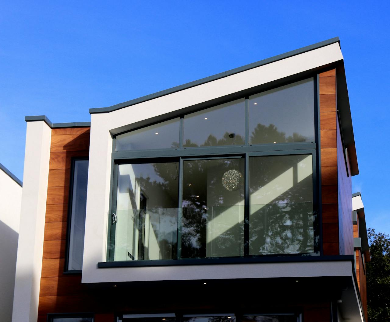 why-choose-us Contemporary house in Poole, UK featuring a sleek design with large glass windows and wood paneling.